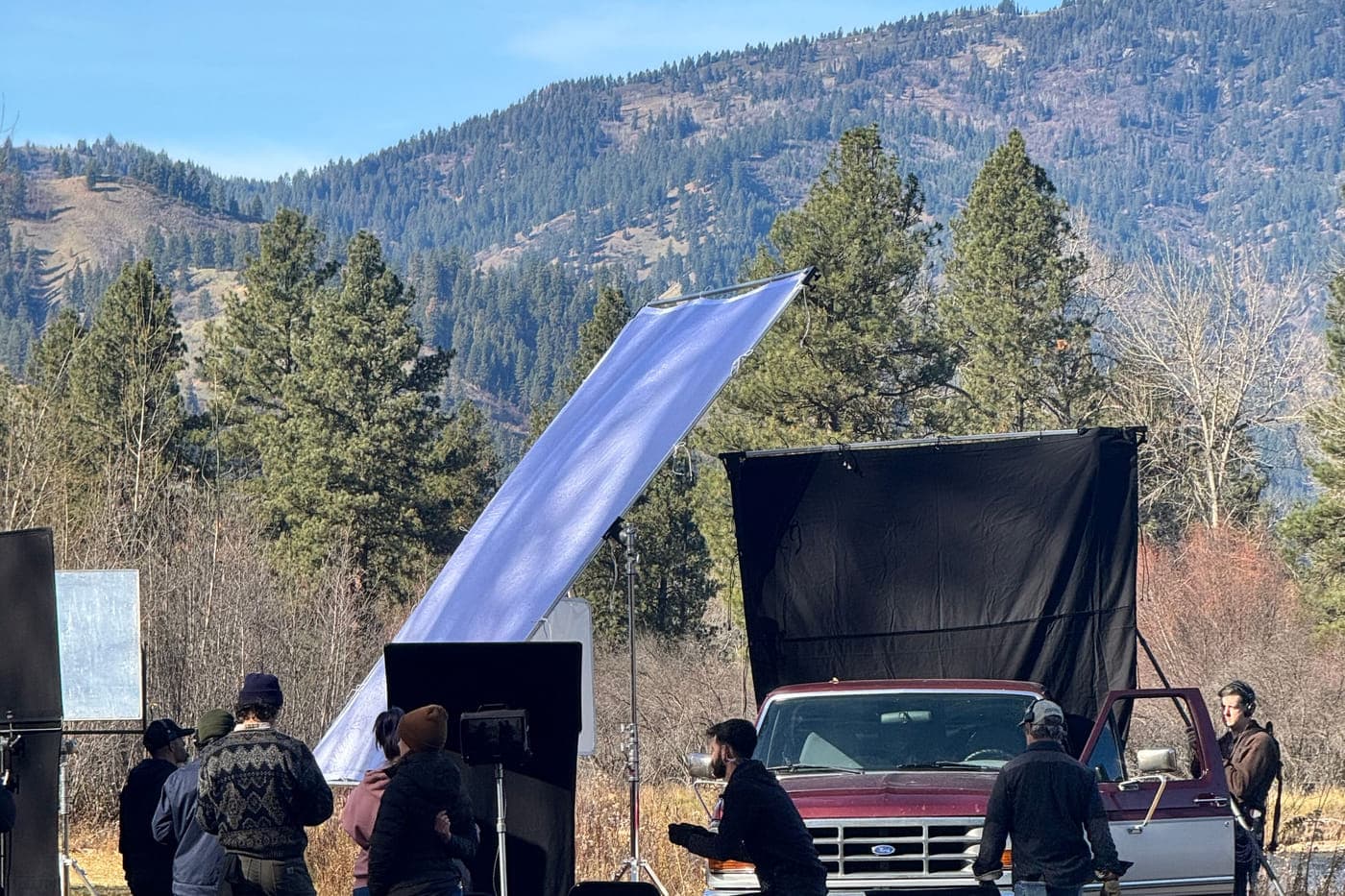 A location setup with a silk, a solid and a picture vehicle below a forested ridge