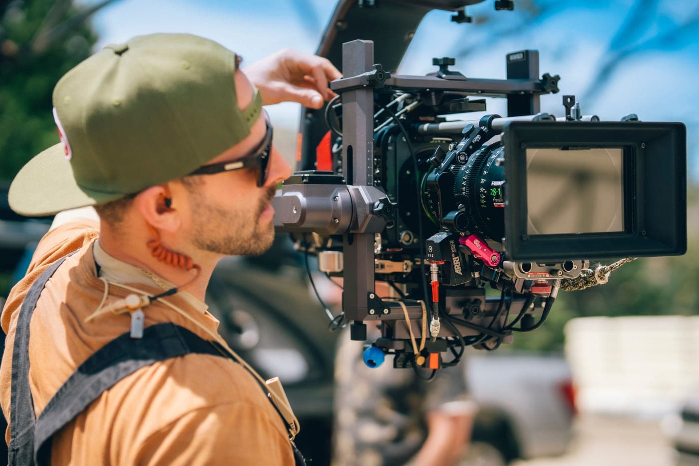 An operator setting a camera and zoom lens on a vehicle mount, outdoors